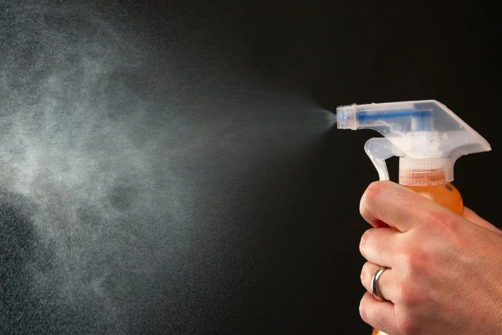A person using a spray bottle on a black background